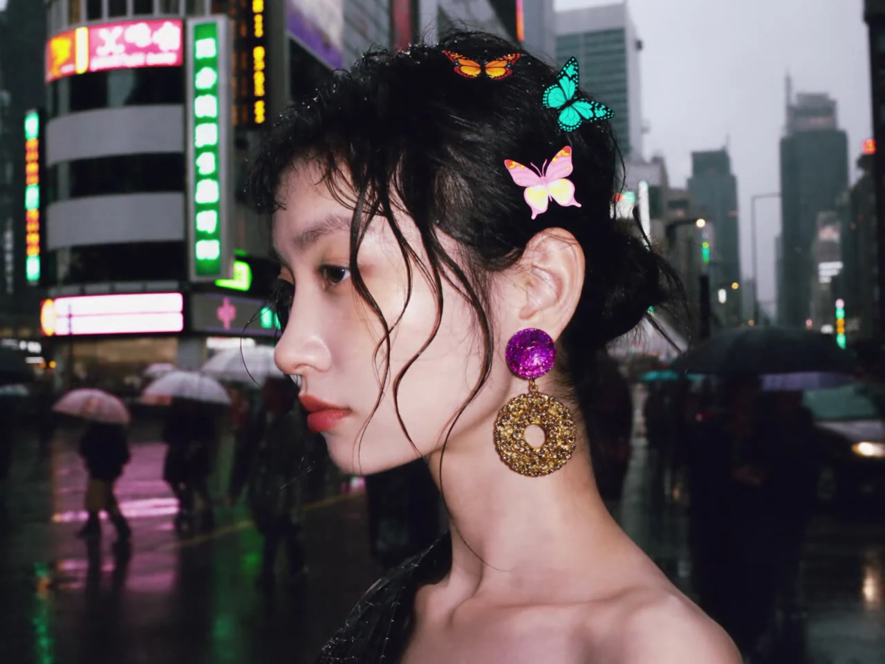 A woman's profile with colorful earrings on a neon-lit street at night